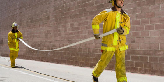 two firefighters holding a long white hose